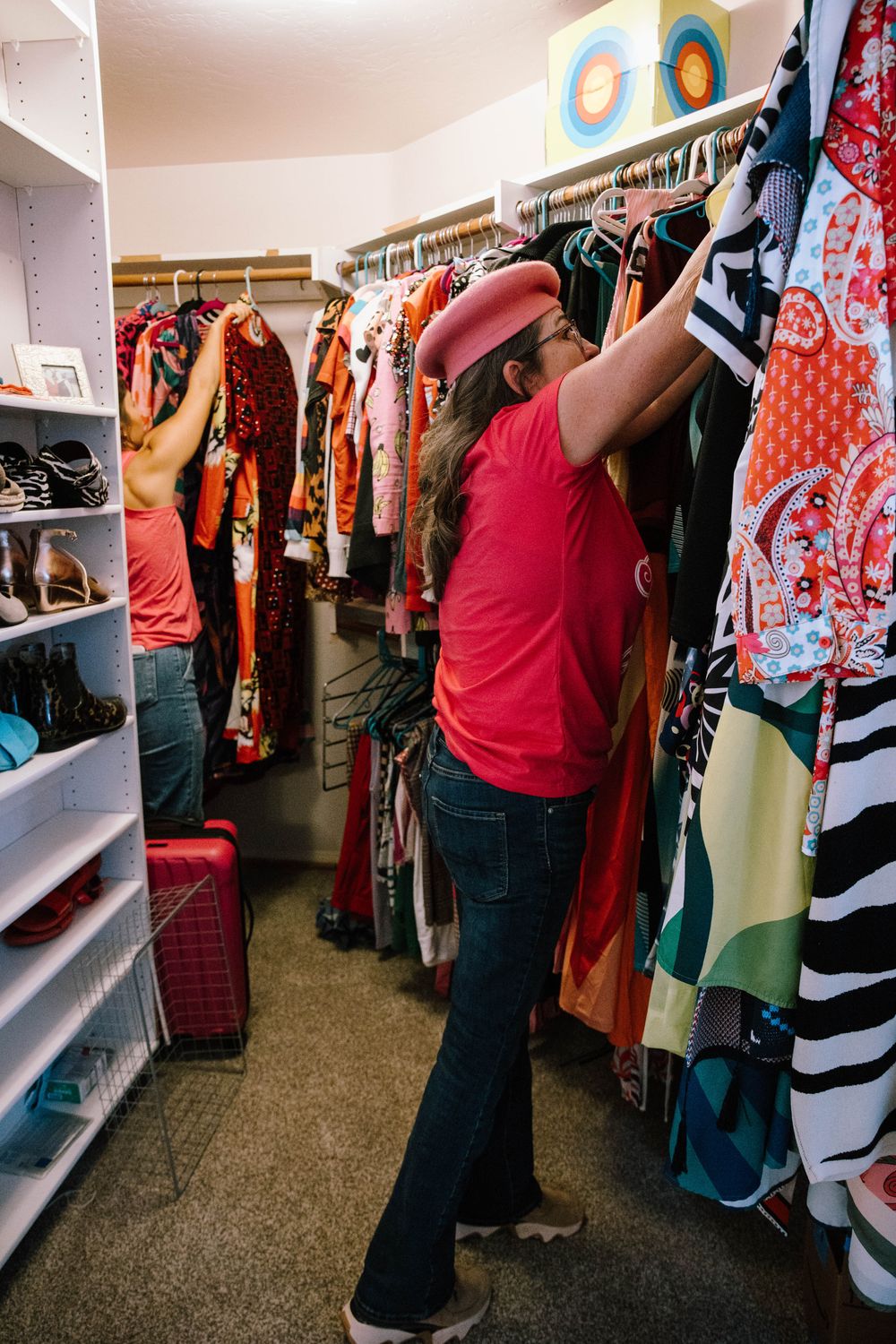 Two Go Goddess organizers working in a closet full of colorful clothes