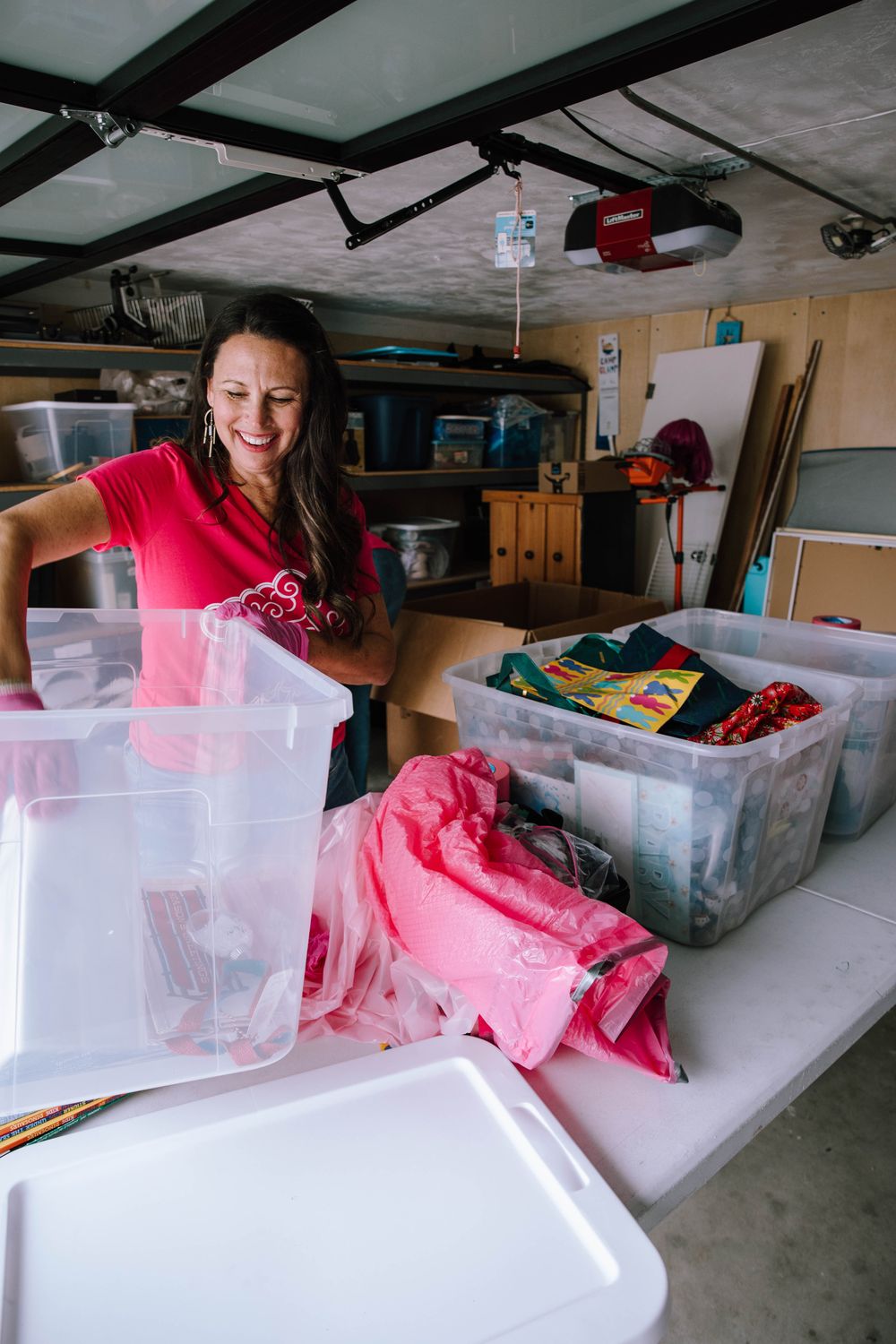A smiling Go Goddess organizer sorting bins in a garage